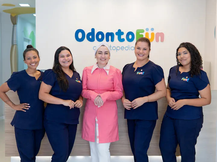 Dra. Bruna Meotti, de jaleco rosa, com a equipe da Odonto Fun na recepção da clínica